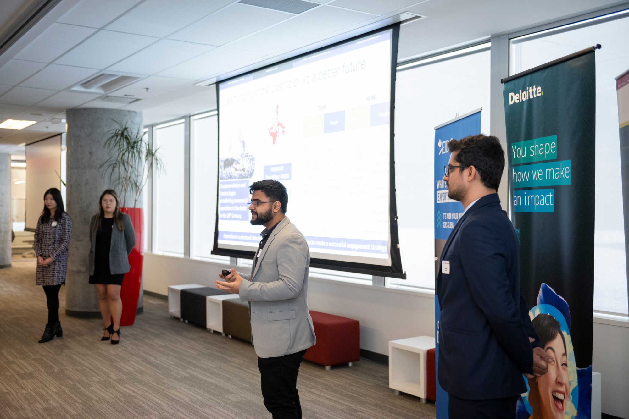Presenting at a case competition, with Deloitte and AEDC banners in the background